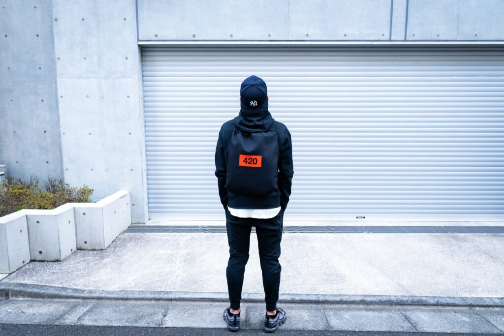 man in black hoodie and blue denim jeans standing on gray concrete floor