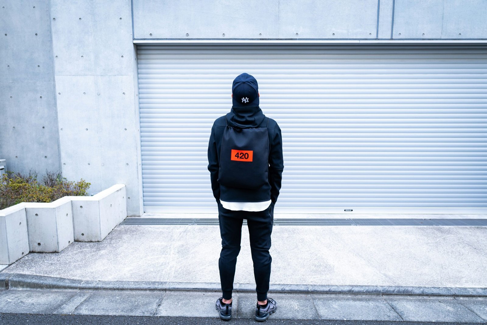 man in black hoodie and blue denim jeans standing on gray concrete floor